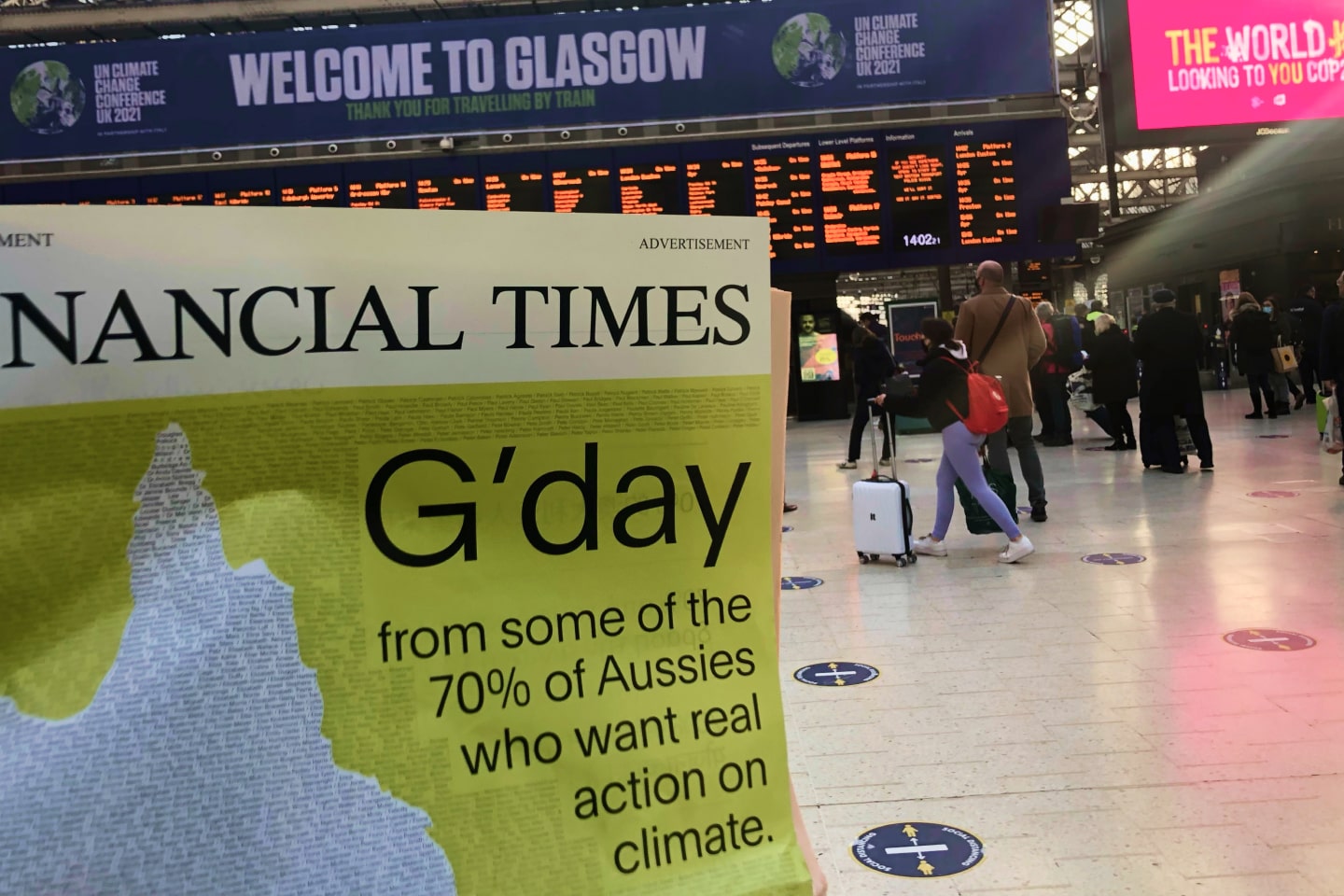 Glasgow Airport with a person holding a copy of the Financial Times newspaper whose headline is about how Australians want climate action